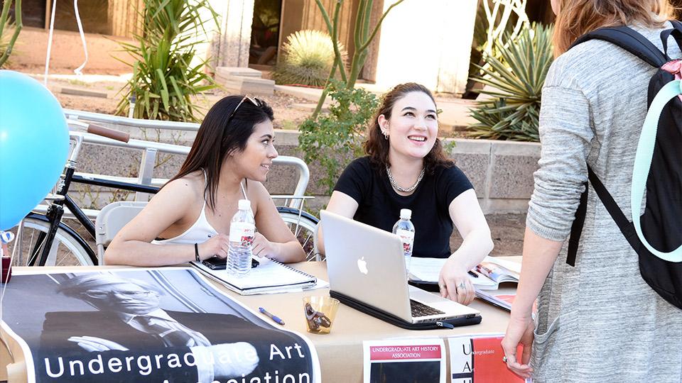 Students sitting behind a folding table